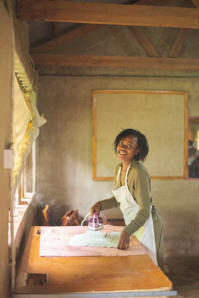 A cheerful woman in an apron irons clothes in a rustic indoor room. Bright and warm atmosphere.