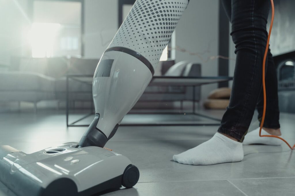 Person vacuuming a tiled floor with a modern appliance in a bright indoor setting.