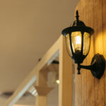 Classic lamp on black wall, vintage filtered image.